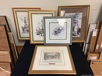 Five framed prints displayed on black cloth with boxes and other frames in background. Trisha Romance print flattest foreground print with gold plaque title 'White Christmas'.
