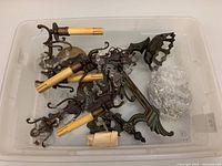 Two vintage brass 2-light wall sconces partially disassembled and stored in plastic bin with crystals, parts visible.