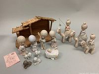 Full set with wooden stable and all Precious Moments nativity figurines arranged in front of a neutral background.
