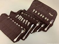 Flatware set laid includes forks, spoons, knives displayed with flatware pouches.