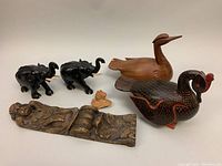 Overview of all six wooden carvings including two elephant sculptures, two ducks, bas-relief cherub plaque, and small cherub figure
