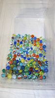 Photo of smaller multicolored glass marbles inside a clear plastic container.
