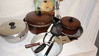 Photo of multiple pots with lids and cooking utensils including spatulas