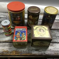 All six tins arranged on wood surface showing branding and size differences