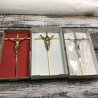 Three crucifixes in individual boxes displayed on wooden surface. Each crucifix approximately 10 inches, new in box.