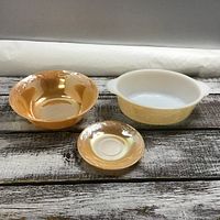 Three peach lustre Fire King bowls on wood surface showing size and shape variations