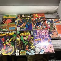 Photo shows 8 vintage comic books laid out on a wooden surface, titles visible and identifiable.