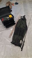 Fishing gear setup including Cabela's waterproof waders, Phantom tackle box with multiple drawers, two fishing poles (one with reel), and various fishing supplies grouped over a floor covering.