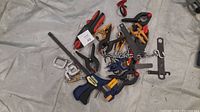 Overview photo showing a variety of clamps and miscellaneous tools scattered on a light gray fabric surface.