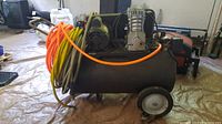 Side view of entire air compressor showing tank, motor, pump assembly, wheels and coiled hoses