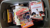 Cookbooks piled inside a storage bin showing titles: Simple Food Big Flavor, Big John's Speedway Grill