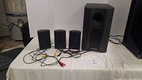 Four Pioneer speakers displayed on a table including three satellite speakers and one subwoofer. Multiple cables visible.