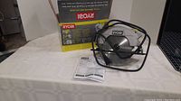 Ryobi 7 1/4 inch circular saw with laser guide displayed alongside the original box and operator manual on a white surface.