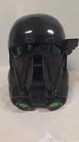 Front view of black Star Wars Death Trooper helmet showing glossy finish and green accent details on respirator area.