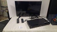 Toshiba 28 inch TV, Sony Blu-ray player with cables and two remotes on a table, front view.