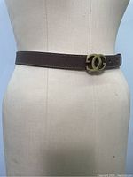 Front view on mannequin showing gold double G buckle and stitching