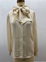 Front view on mannequin showing bow tied at neck and concealed button placket