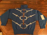 Navy turtleneck sweater laid flat showing front horsebit motif
