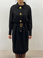 Front view of black Chanel dress on model showing collared neckline, button placket, and belt detail.