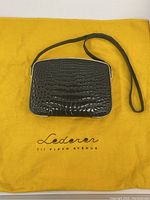 Purse and dust bag laid flat showing brand logo on bag and dust cover