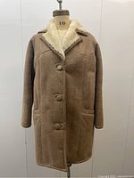Front full-length view of beige sheepskin coat on mannequin
