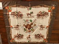 Full view of square scarf laid flat showing border and equestrian motif