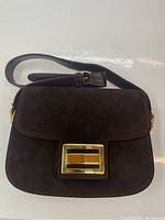 Front view of dark brown suede bag with flap closed and strap in position