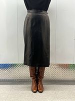 Front view of black leather midi skirt on mannequin showing length and fit