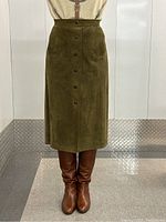 Front view of olive green suede skirt on model showing full button placket and pockets