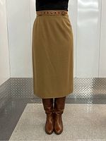 Front view of skirt worn on model showing A-line silhouette, camel wool fabric and leather belt.