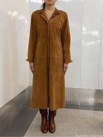 Front view of tan suede garment on model, showing length, fit and concealed closure