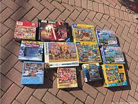 Full overview of assorted puzzle boxes on brick ground showing box artwork and puzzle piece counts.