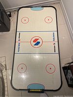 Top-down view of the air hockey table top surface with markings and logos visible.