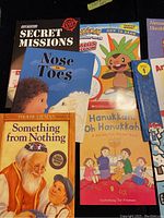 Photo showing assorted children's books including Secret Missions, Nose to Toes, How to Draw Pokémon, Hanukkah Oh Hanukkah, Something from Nothing.