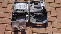 Both Dremel tools in open gray hard plastic cases displaying tools, cords, manuals, and two extra cutter packs in plastic.