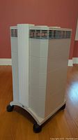 Full front and side view of grey IQAir HealthPro Series 101.6 air purifier on caster wheels, showing ventilation grills and general shape.