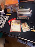Full display of the Marcato pasta maker with attachments and instruction leaflets spread on table.