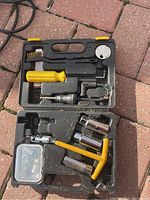 Full view of spark plug maintenance tool kit in open black plastic carrying case showing various metal tools including sockets, brushes, and plastic handled T-handle tool along with a small plastic parts box.