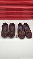 Two pairs of men's burgundy leather moccasins displayed side by side on a white surface.