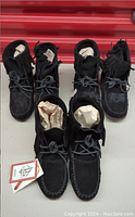 Three pairs of black suede moccasin boots displayed side by side, showing the full front and upper portions including fringe and laces.