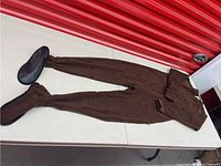 Full view of the brown fleece footed pajamas laid out flat, showing the single zipper and overall design.