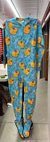 Full front view of blue fleece footed pajamas with yellow rubber duck and bubble pattern, front zipper visible.