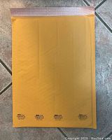 Single gold-colored bubble mailer displayed flat, showing self-seal adhesive strip on top edge and padded bubble interior texture visible through color.