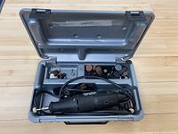 Opened plastic case containing Dremel 3950 rotary tool with power cord and numerous accessories inside compartments