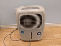 Front view of a white Honeywell dehumidifier showing air intake grille, water level window, and brand label.