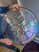 Full view of circular panel held by hands against wall