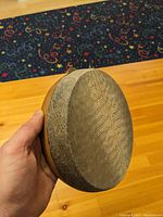 Hand holding the kanjira showing natural lizard skin drum head and wooden frame.