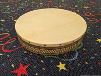 Side view of Middle Eastern frame drum showing leather skin and decorative wooden frame inlay.