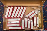 Box showing 18 resonator bells in total, 10 for C notes and 8 for G notes, arranged with visible red sides and white tops.