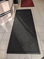 Large black rubber-backed mat with waffle pattern, shown on tiled floor